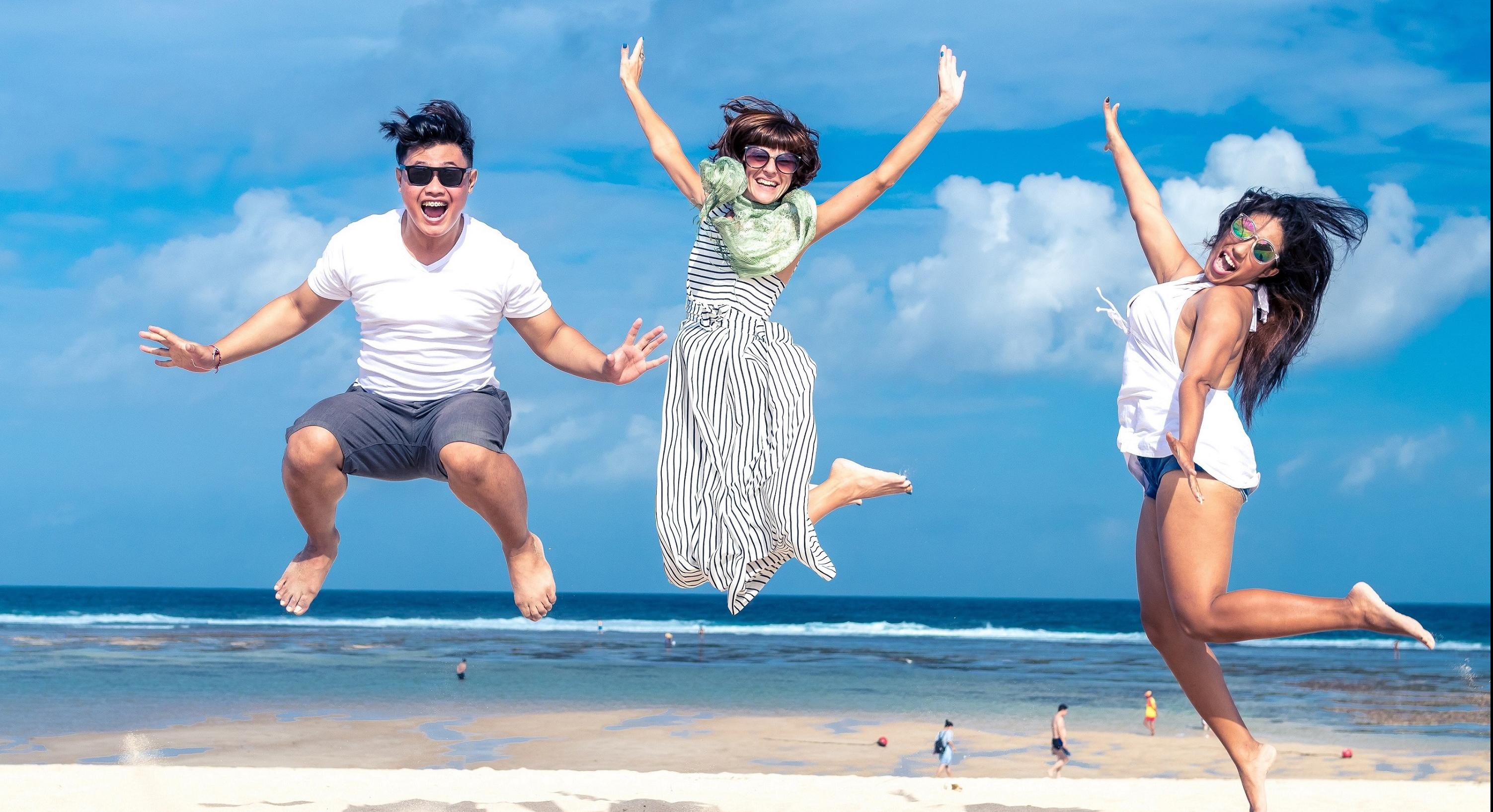 three happy people jumping on the beach